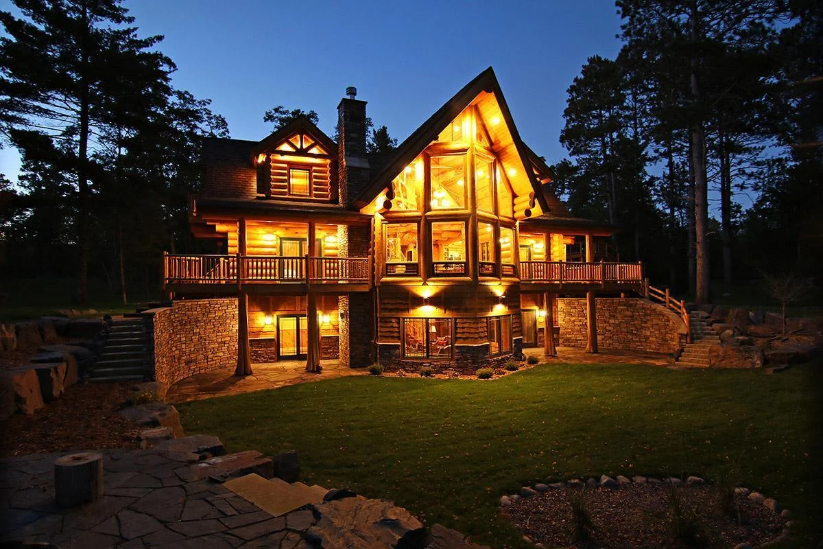Twilight photo looking at the home from the elevated fire pit area