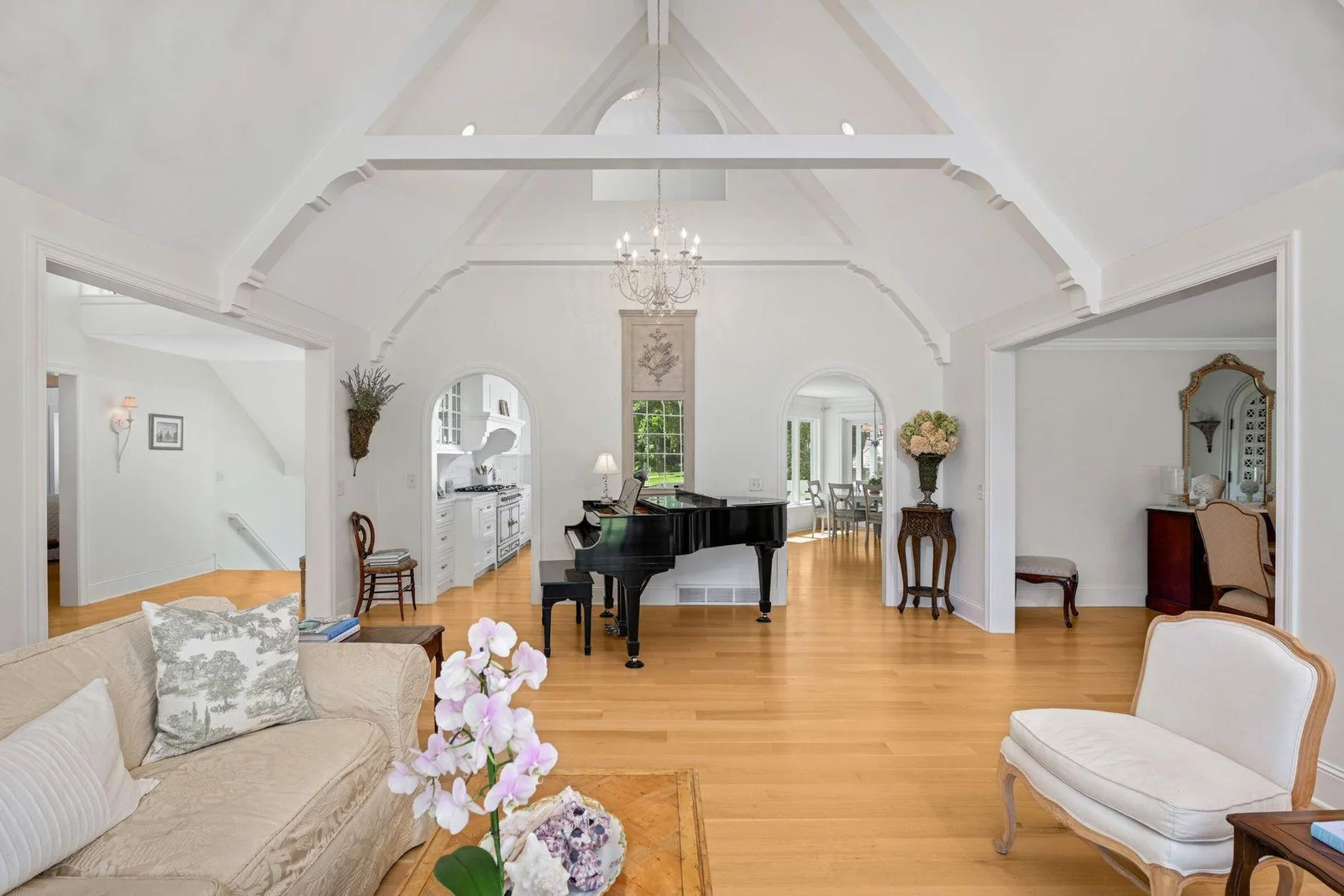 The living room opens to the dining room (on the right), and carries the repeated arch through the upstairs and arched openings into the kitchen/family room.