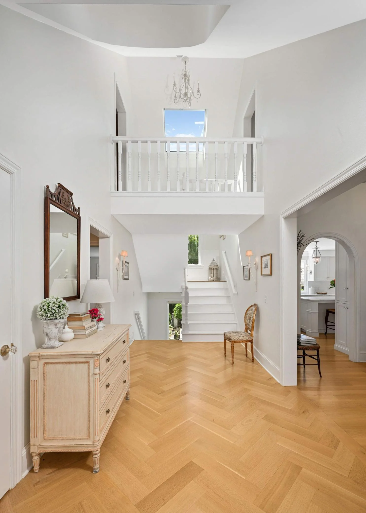 Greenery and light spills from nearly every direction in the foyer, which opens to the staircase. To the left is the mudroom and primary suite, to the right is the living spaces.