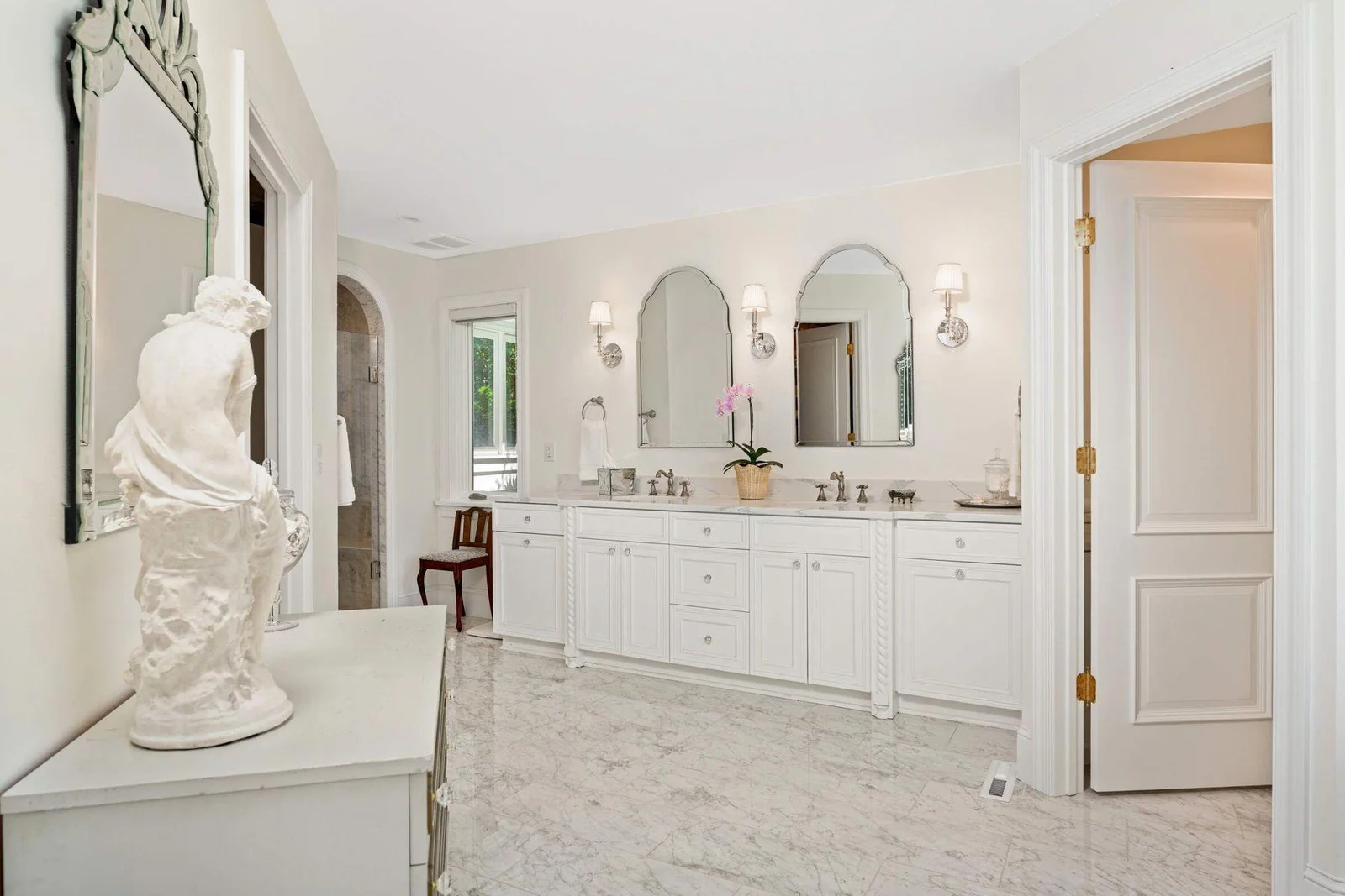 The owner's suite consists of dual sinks and private water closet (door on the right), walk-in closet (to the left) and arched marble shower. Beautiful custom cabinetry at vanity, and also in water cl
