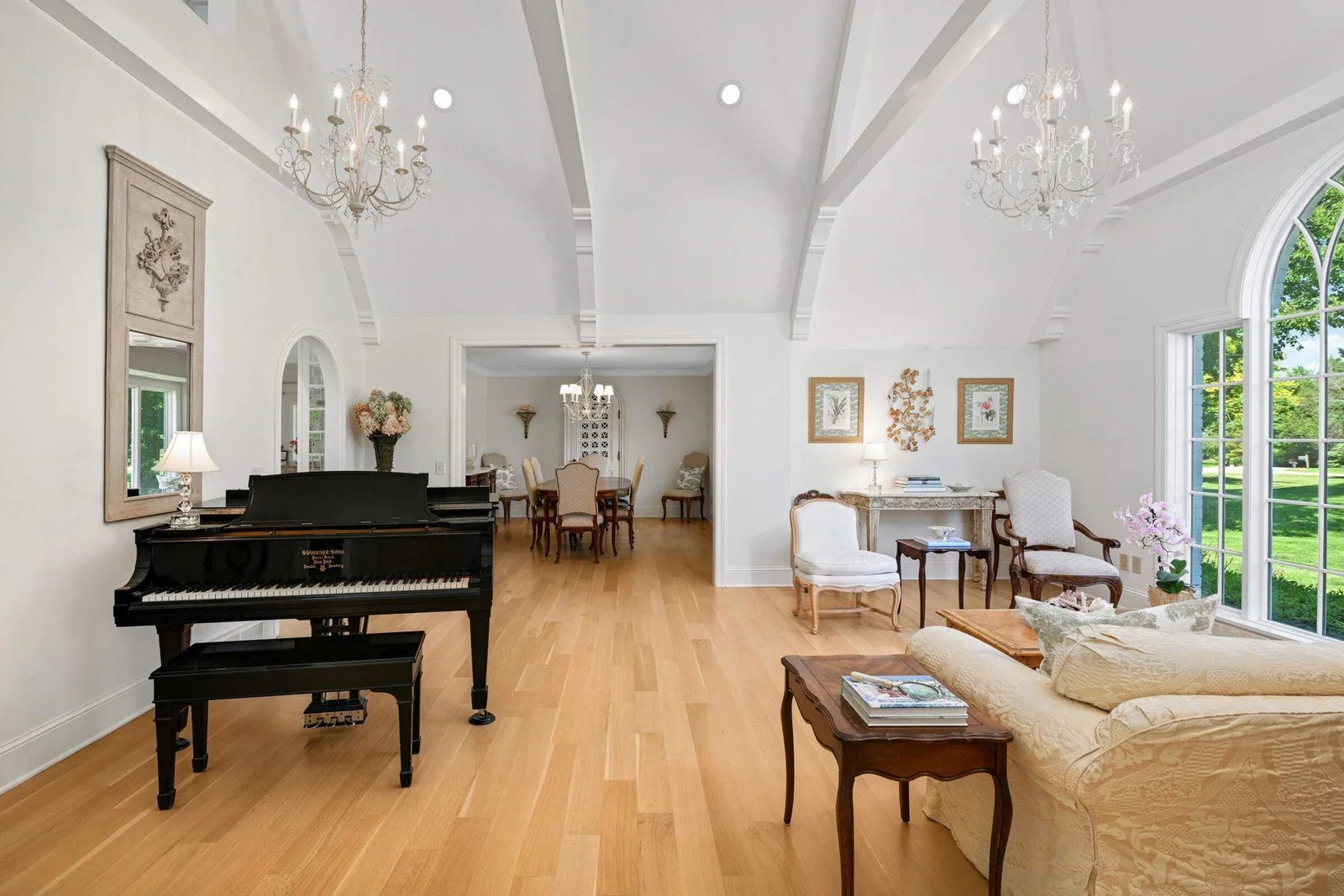 The living room features the dramatic Palladian window, white oak floors, and cathedral ceilings with exposed beams.