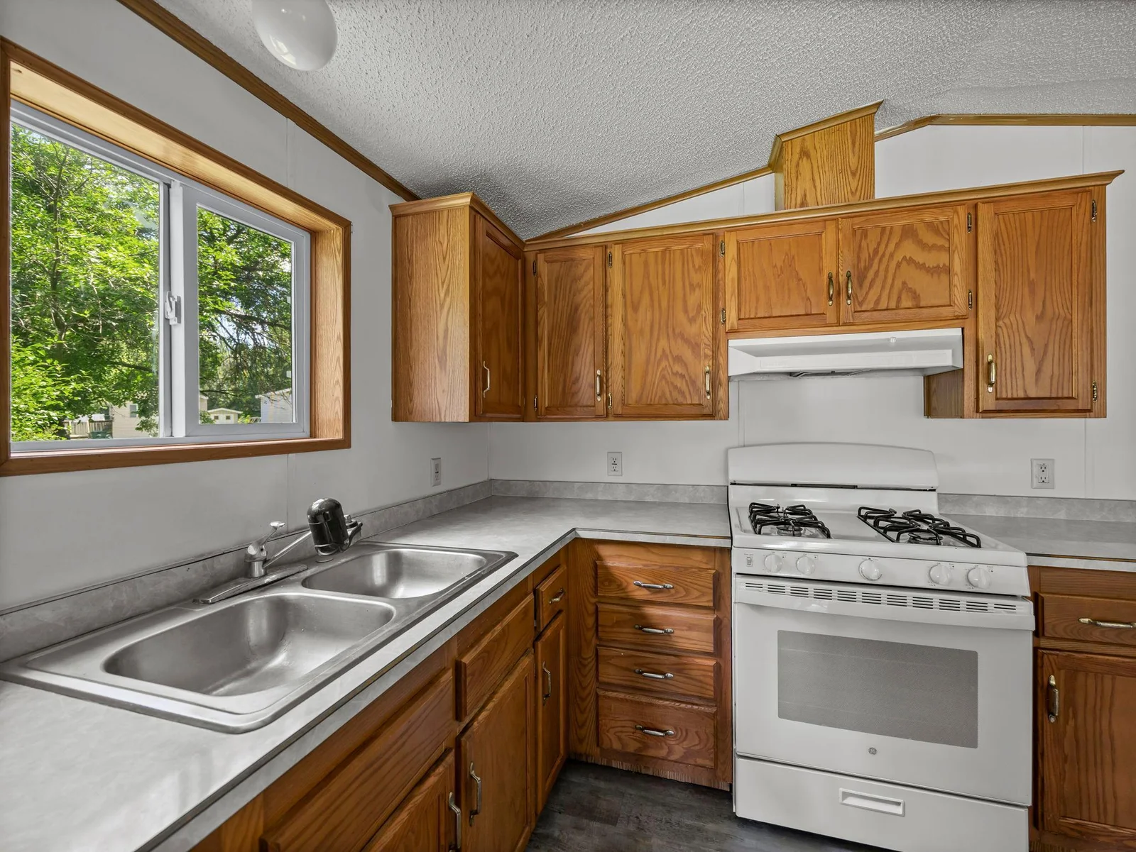The kitchen features oak cabinets, laminate countertops, LVT flooring, and a gas range.