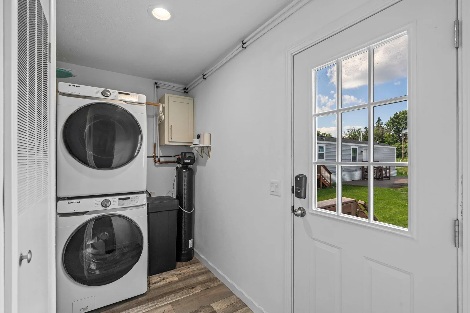Completing the interior is a finished, dedicated laundry room with stacked Samsung washer and dryer, upper cabinetry for easy storage, and direct access to the yard.