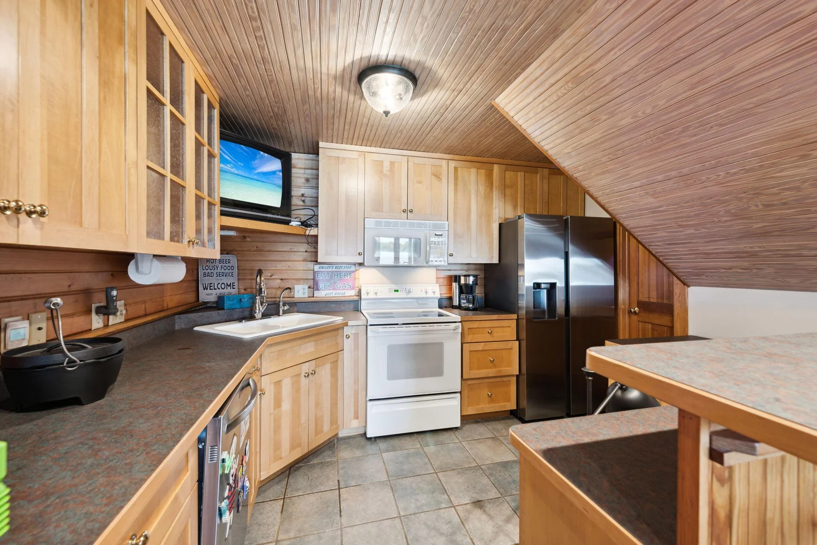The second kitchen in the walk-out lower-level features full-size appliances, including a dish washer, ample cabinetry, and bar seating. Ready for lakeside entertaining or hosting extended stays with ease and convenience.