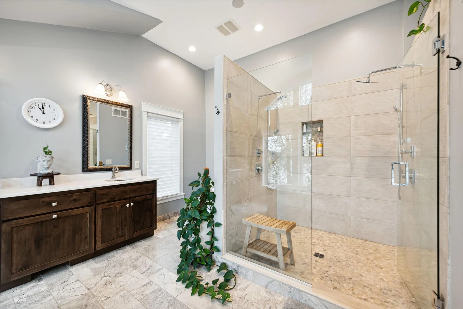 This spa-inspired bath features a luxurious walk-in shower with dual showerheads, built-in bench, and stunning tilework, offering comfort, style, and relaxation in every detail.