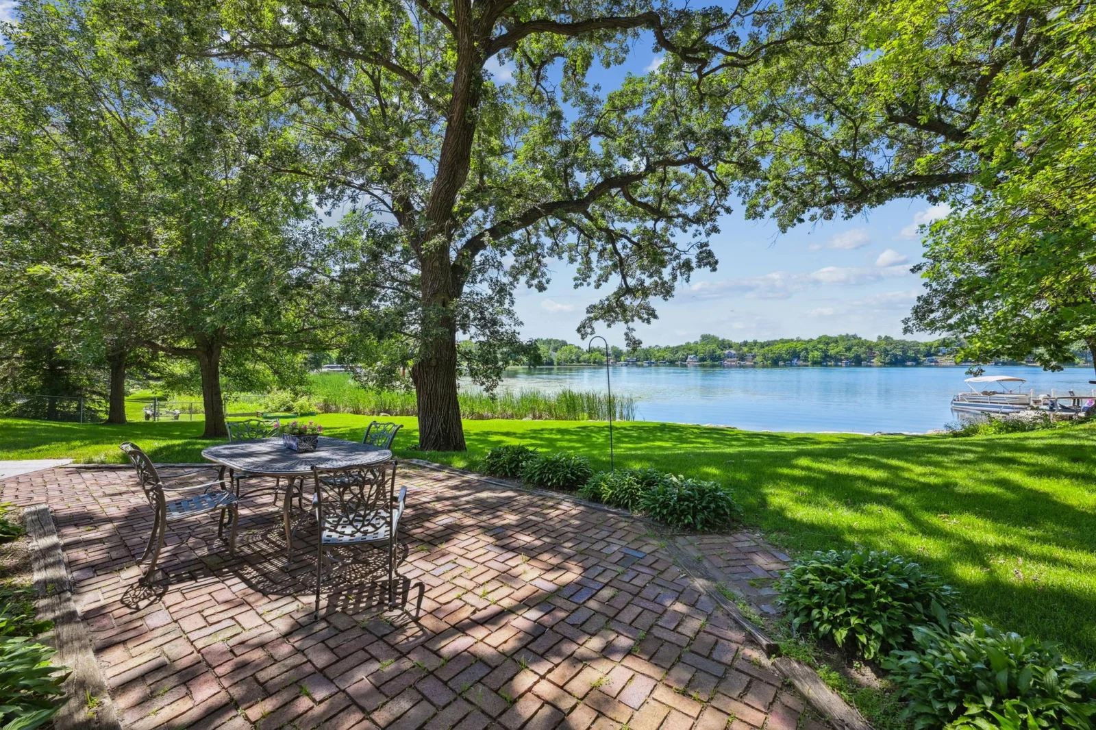Charming brick patio shaded by mature trees with panoramic views of Lake Sylvia. The perfect spot for outdoor dining, morning coffee, or sunset relaxation just steps from the shoreline in this exceptional lakeshore retreat.
