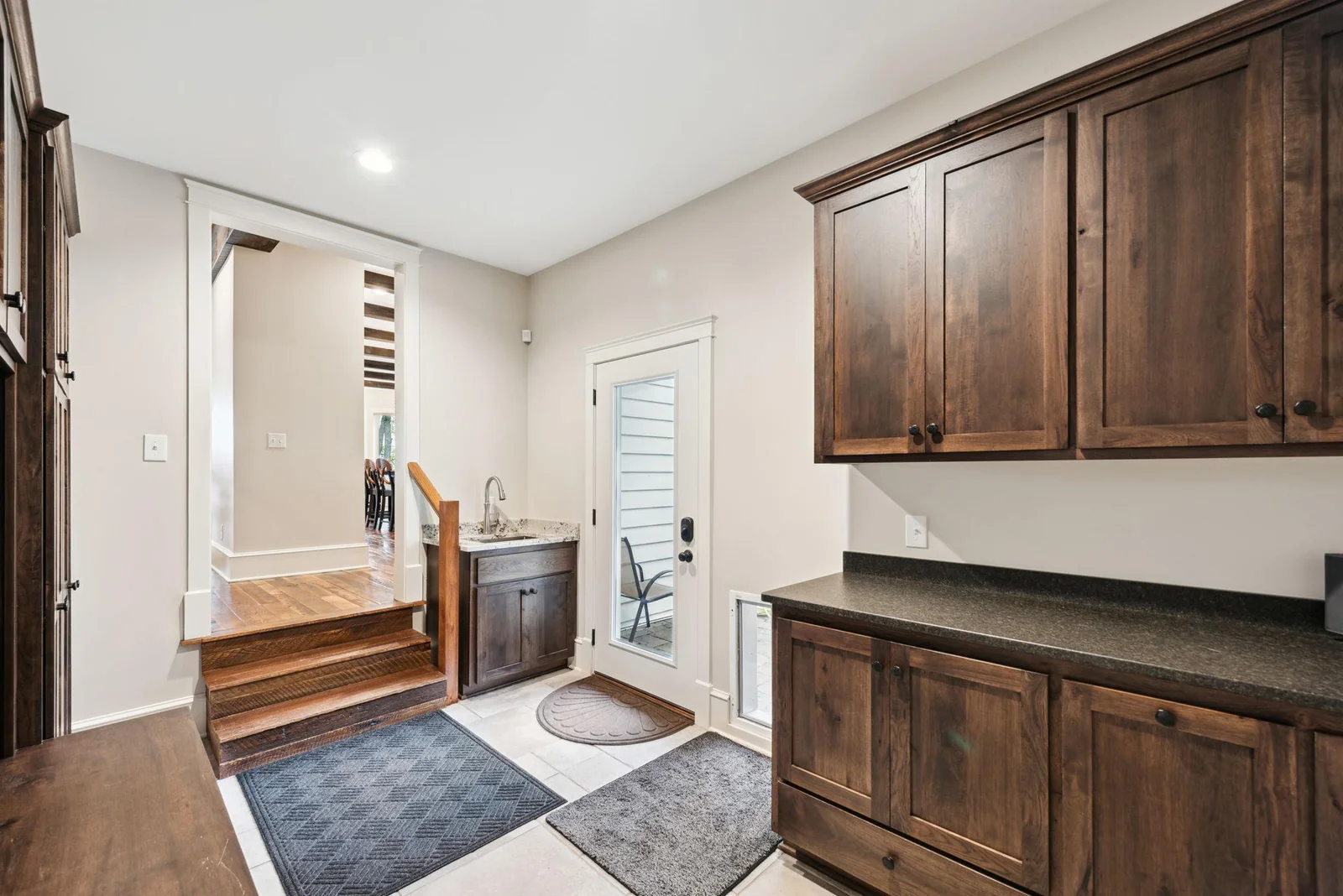 This spacious mudroom between the kitchen and attached garage features custom cabinetry, built-in lockers, and a convenient sink helping you stay organized in your day-to-day life.