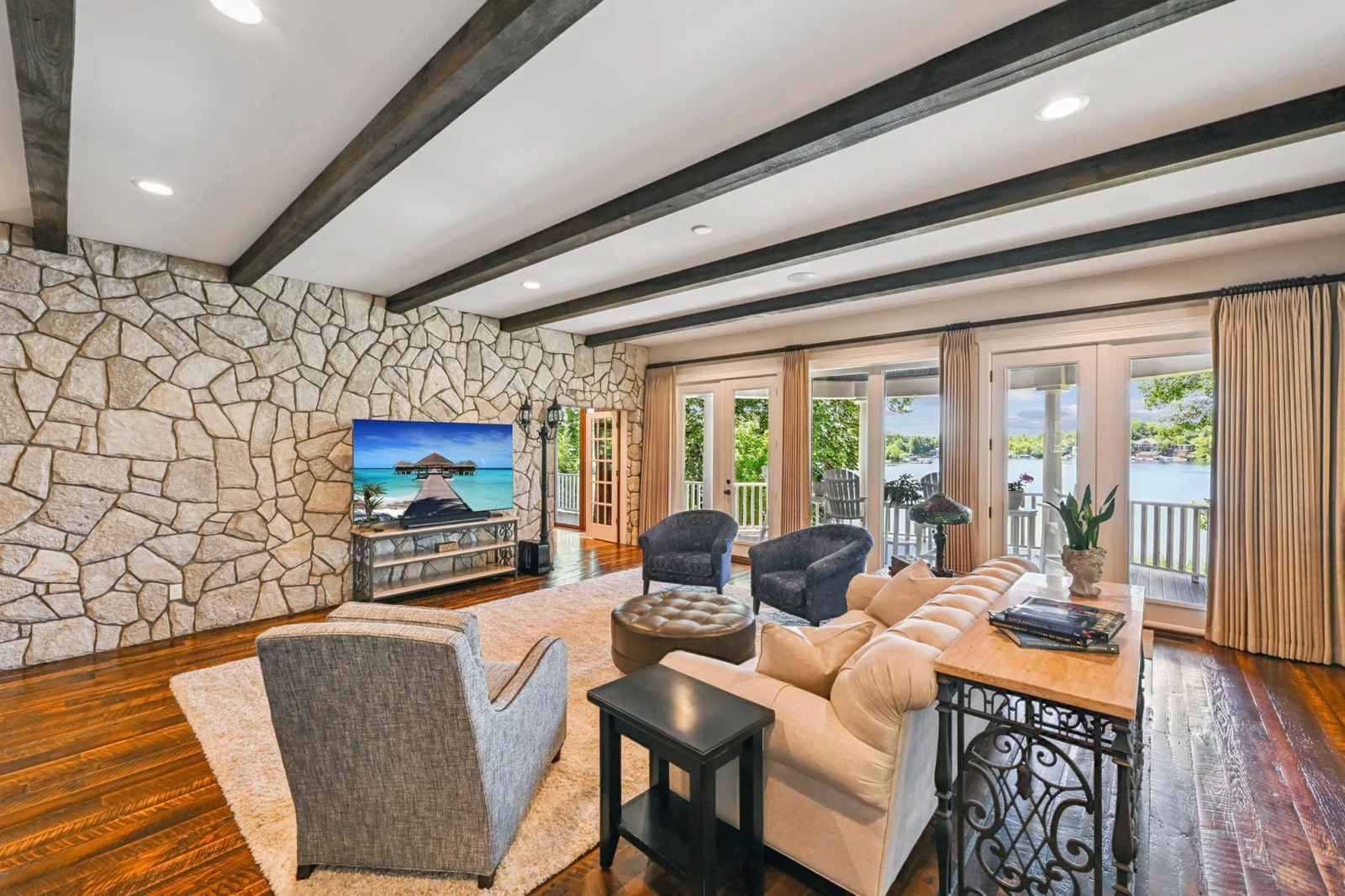 Enjoy stunning lake views from this sun-drenched great room, featuring a full stone accent wall, barn wood flooring, and a wall of picture windows & doors leading to the expansive lakeside covered deck. Porch doors and windows replaced in 2019.