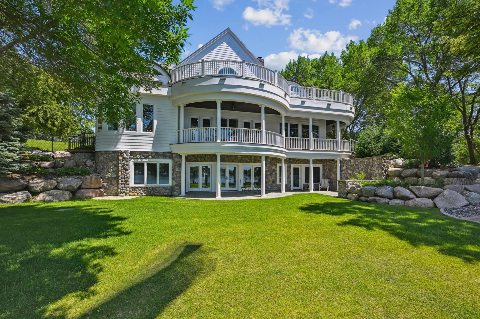 Showcasing timeless architectural elegance, the lakeside of this West Lake Sylvia estate features stunning curved balconies, stacked covered porches, and classic white railings that create seamless indoor-outdoor flow across three levels.