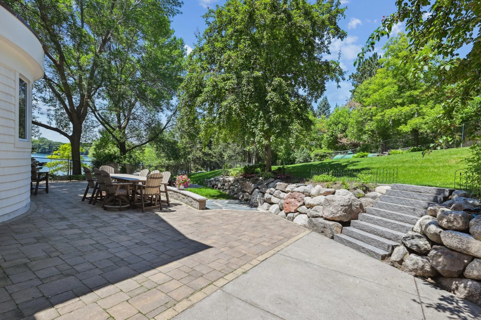 The paver patio wraps behind the garage, offering convenient access to both the mudroom and garage through patio doors, ideal for seamless indoor-outdoor living.