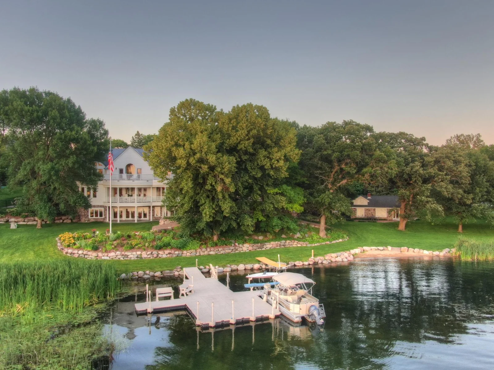 Iconic West Lake Sylvia estate featuring nearly 400 feet of shoreline, private docks, tiered gardens, and a charming guest cottage all with golf cart access and no steps to the water. A rare blend of luxury and lakeside ease.