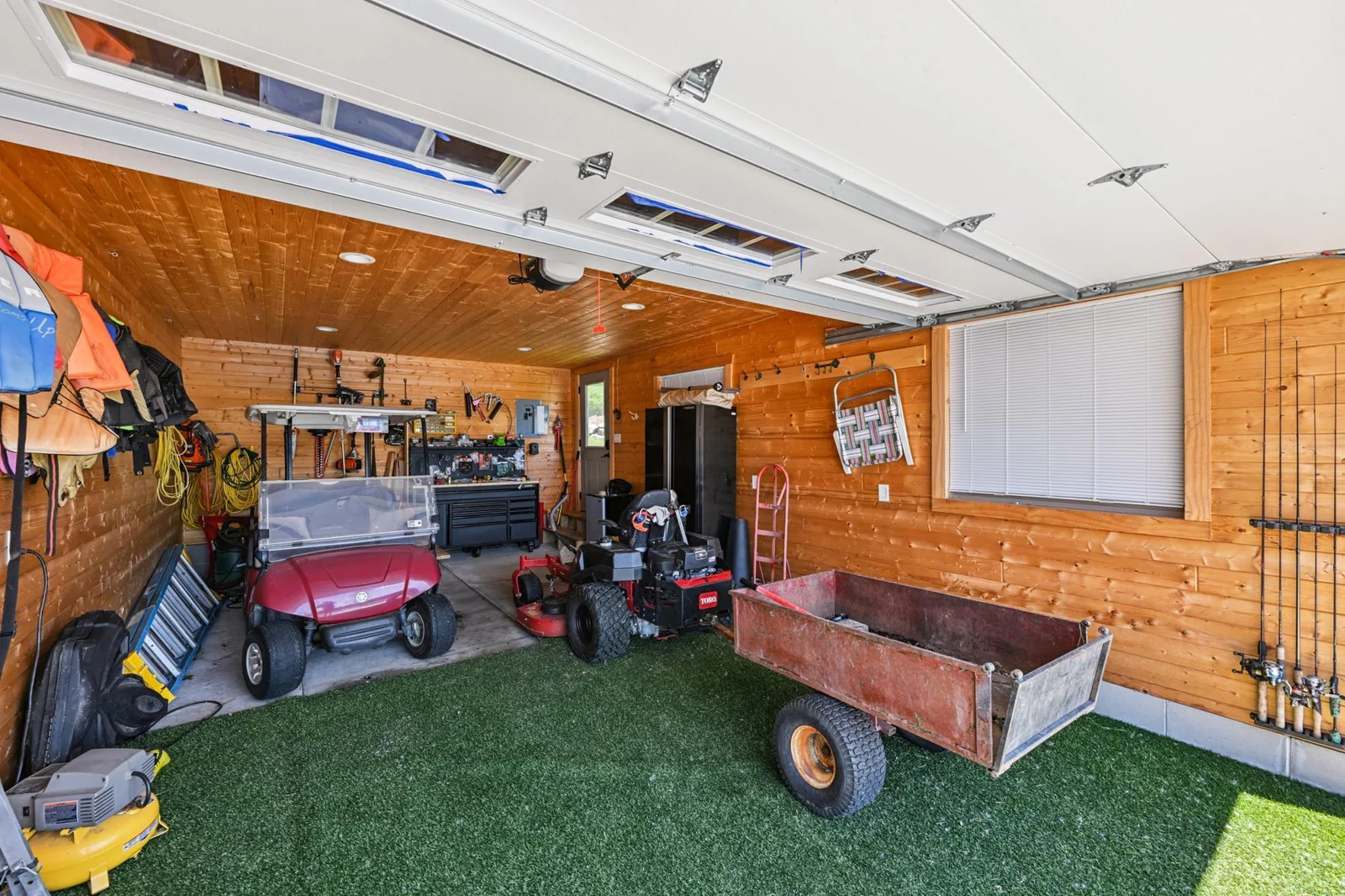 Interior view of the boathouse featuring a 7.5x14 overhead door, tongue-and-groove walls, and ample space for lake gear, tools, and toys—ideal for effortless lakeside living.