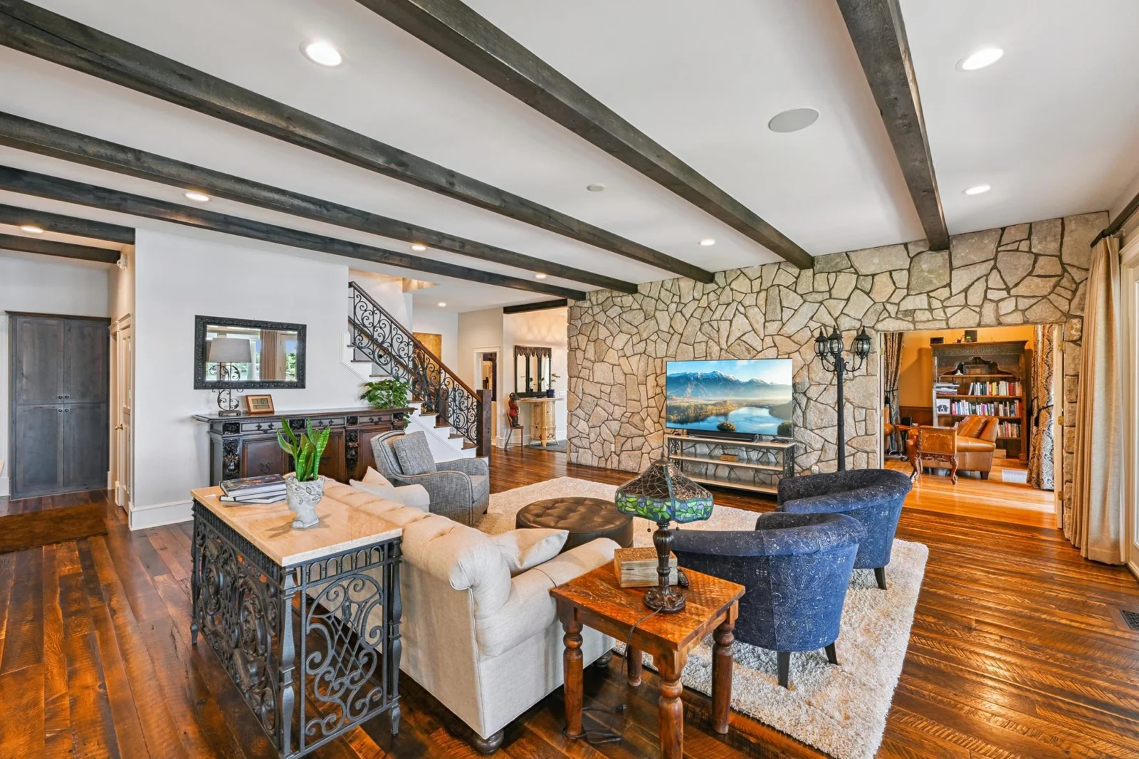 The main floor great room is the perfect gathering space for family and friends, featuring rustic beams, a stunning stone accent wall, and plenty of room to relax after a day on the lake.