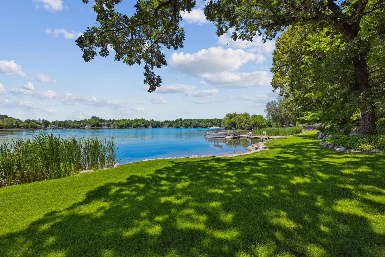 Mature trees provide dappled shade over a lush, level lawn that stretches to the water’s edge. With panoramic views, tranquil surroundings, and easy water access, this outdoor space is ideal for relaxing, entertaining, or heading out on the lake.