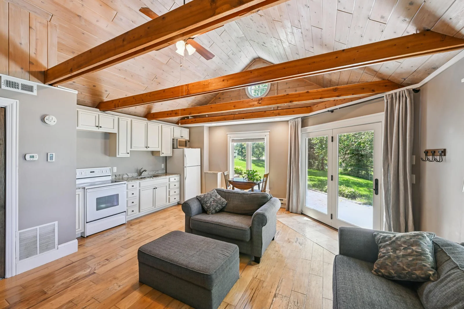 The spacious guest cottage features a full kitchen, and cozy living area with abundant natural light. The large patio door leads to a private patio surrounded by lush greenery, ideal for extended stays or entertaining lakeside guests.