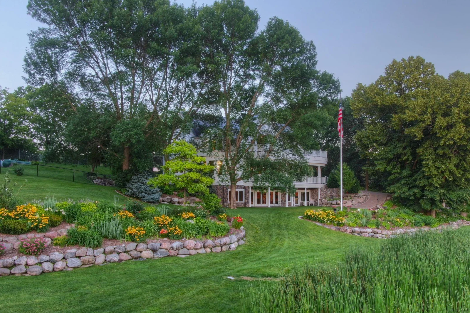 Expansive, gently sloping lawn provides a rare, step-free transition from the home to the lake ideal for easy mobility. Thoughtfully designed landscaping and paver pathways guide you past vibrant gardens and mature trees to the shoreline.