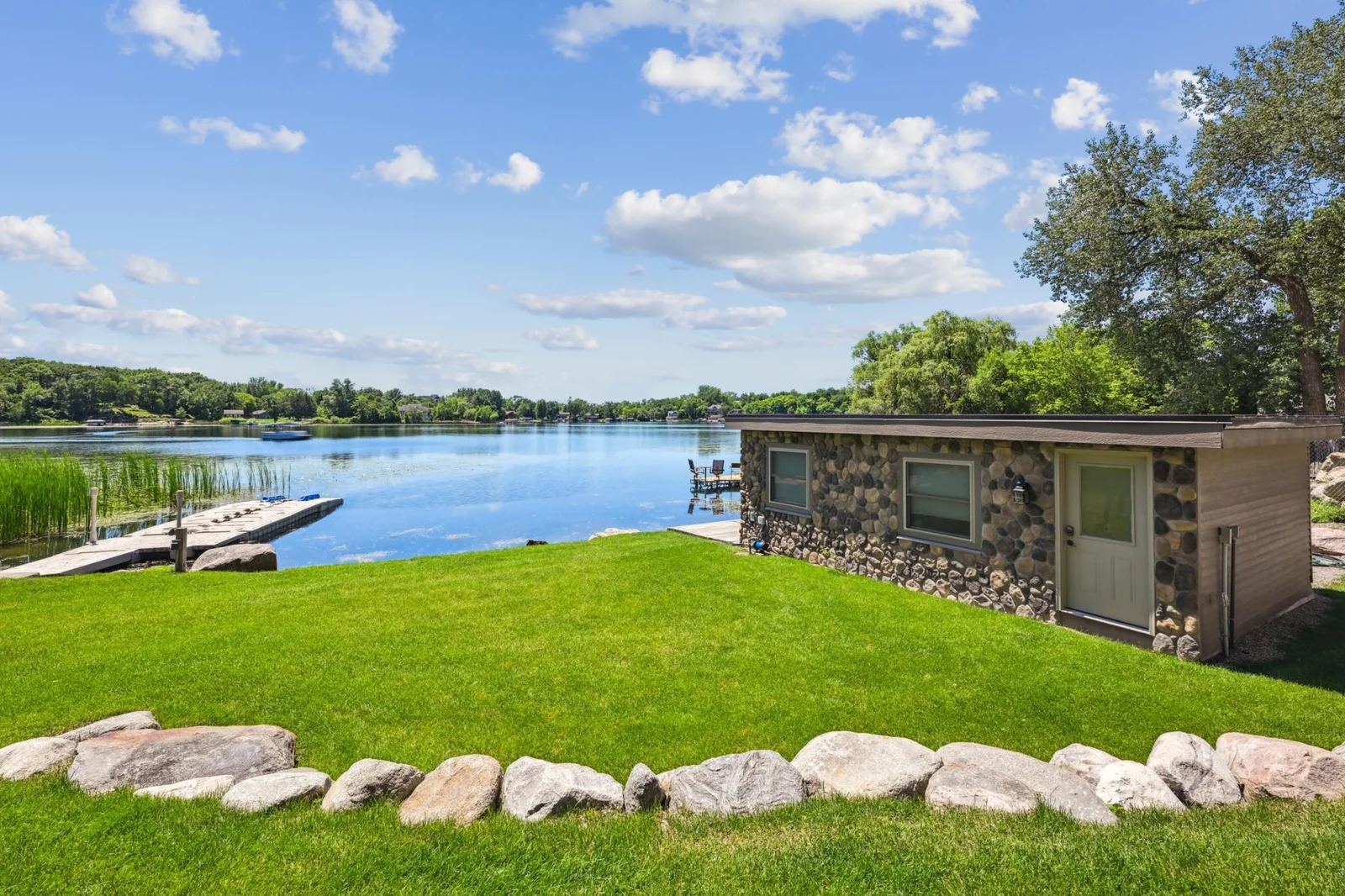 Surrounded by lush lawn and framed with natural stone landscaping, this boathouse provides secure storage for water toys and boating essentials. A rare and highly functional amenity that adds both character and convenience to this extraordinary home.