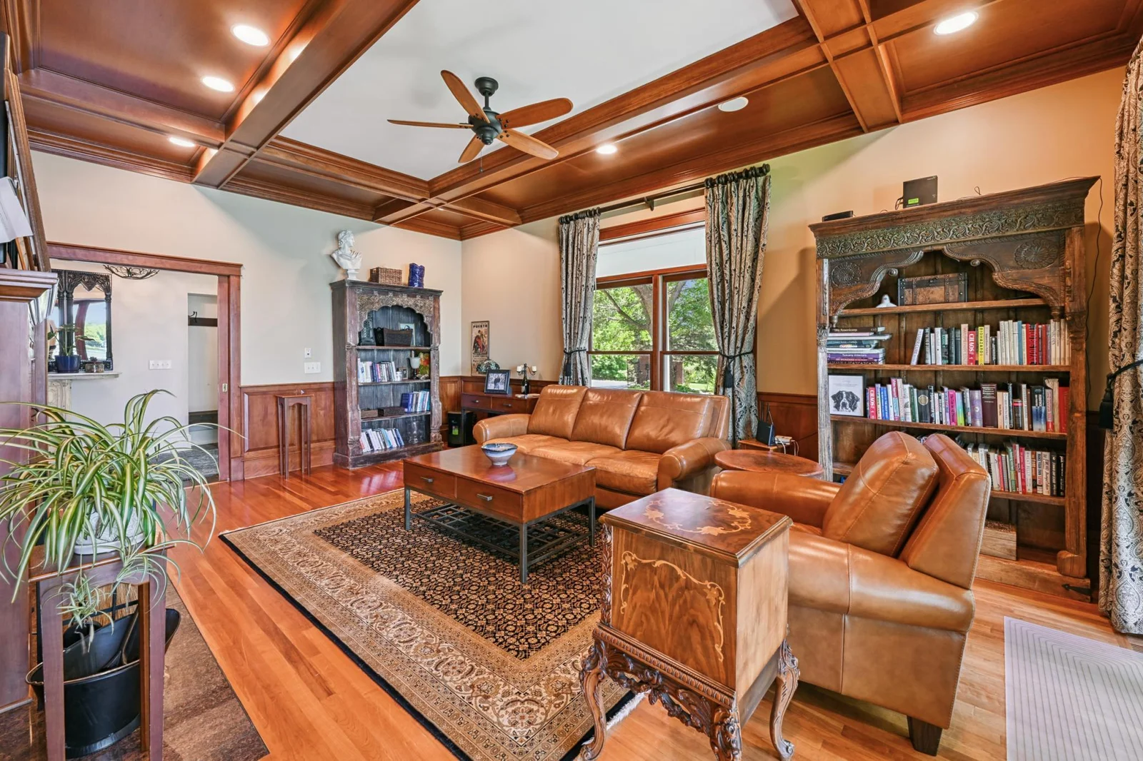This elegant den at the front of the home features a coffered ceiling, hardwood floors, and a wood-burning fireplace—ideal as a study with views of both the lake and the gated drive.