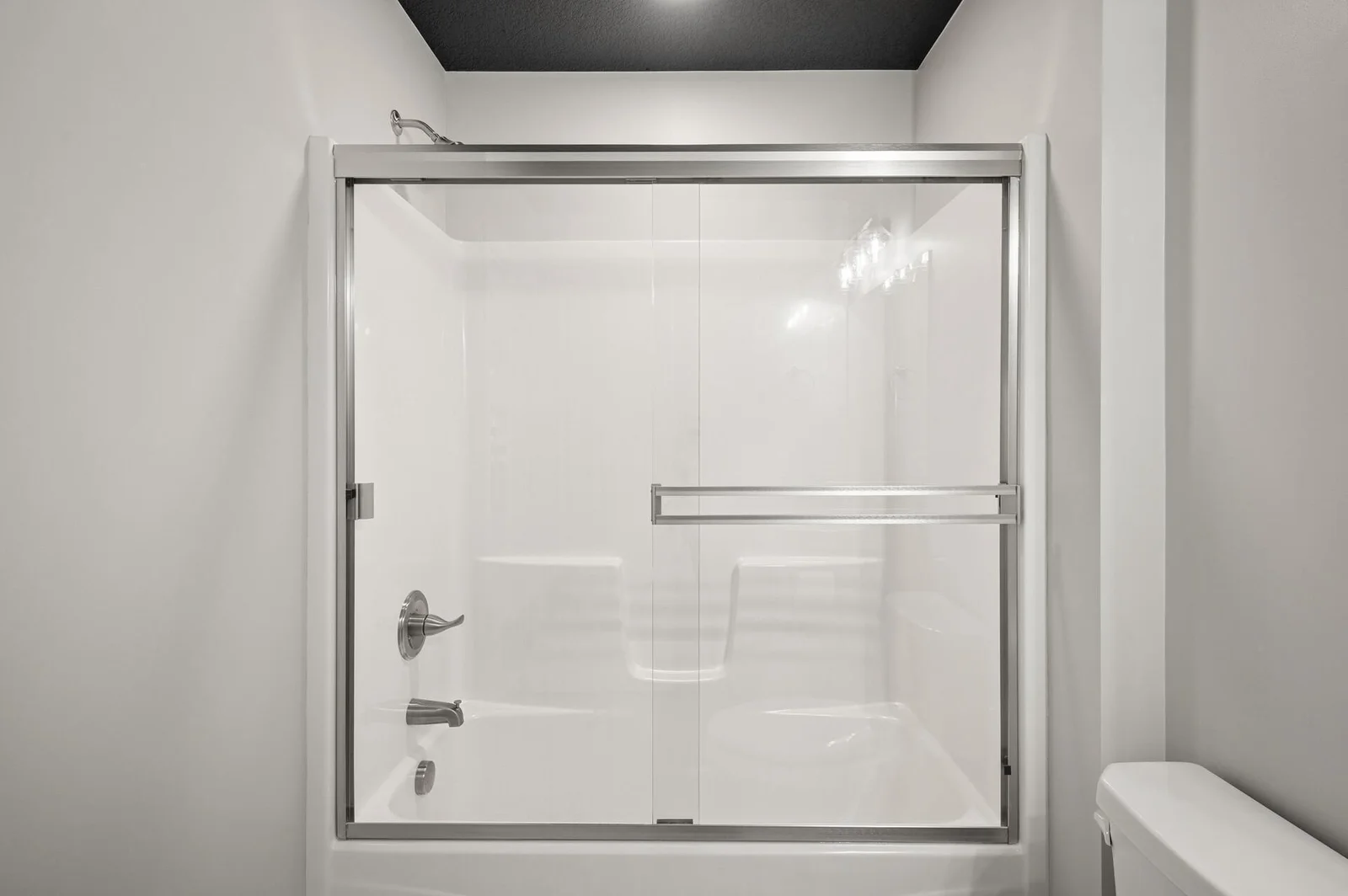 Spotless shower/bath bay with semi-frameless bypass glass doors.