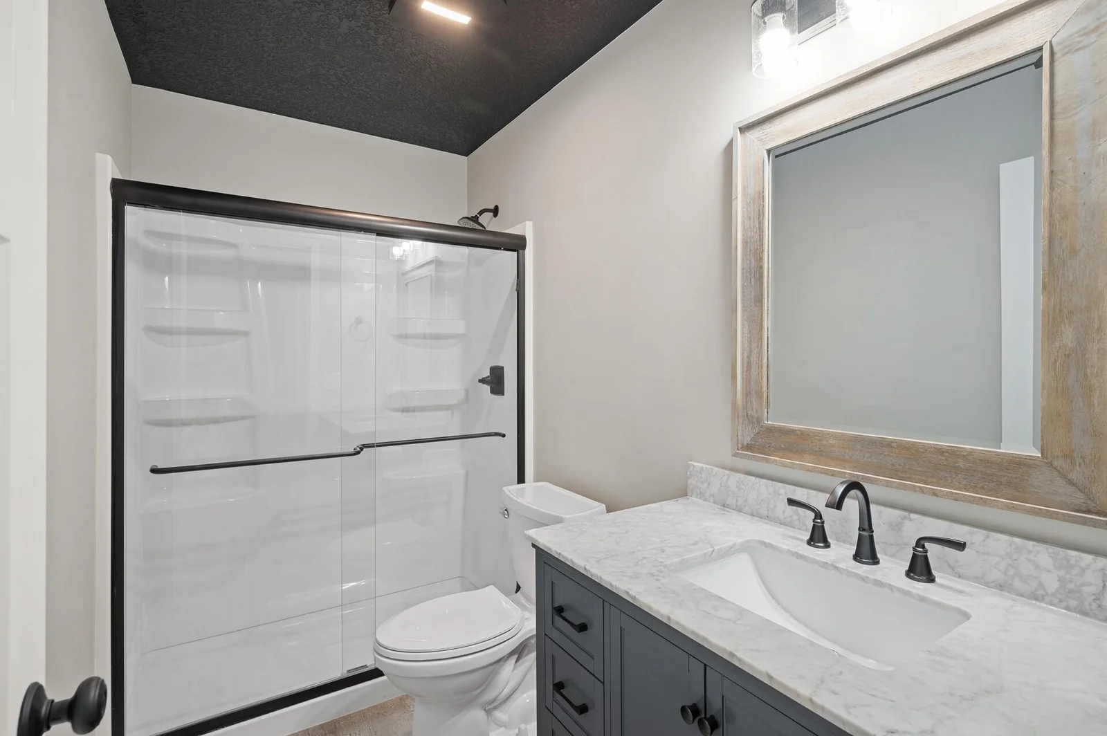 lower level 3/4 bath, quartz vanity, tile flooring and bypass glass shower doors.