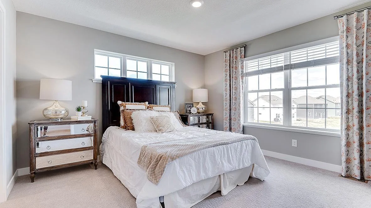 Spacious primary suite with large windows create an open and airy feel. Model picture shown. Colors and finishes may vary.