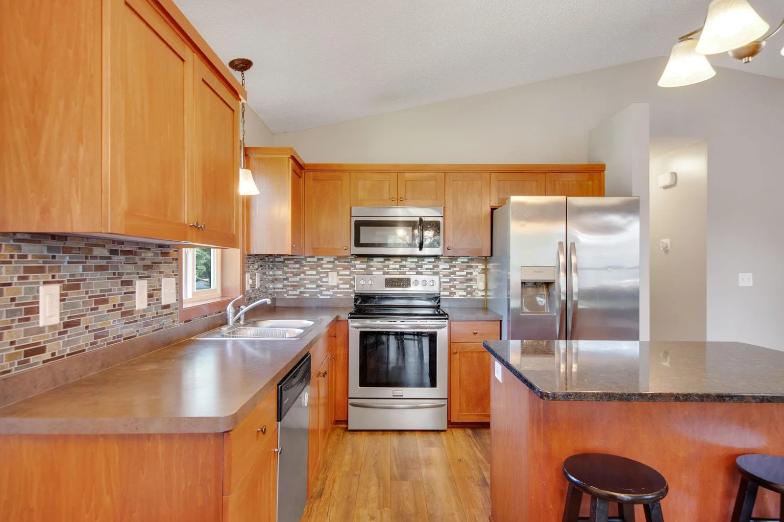 Kitchen features granite island, stainless appliances, and tile backsplash!