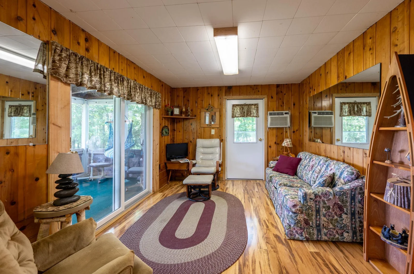 Living room with knotty pine and large sliding door to porch offering exceptional views of the lake.