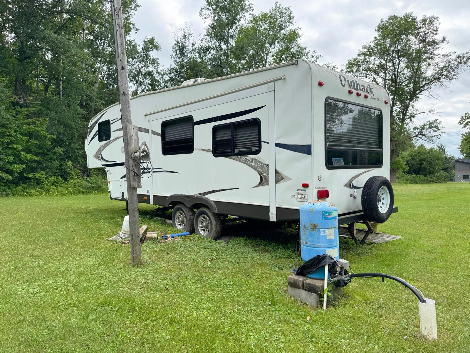 Another angle of the camper's exterior featuring the well/pressure tank.