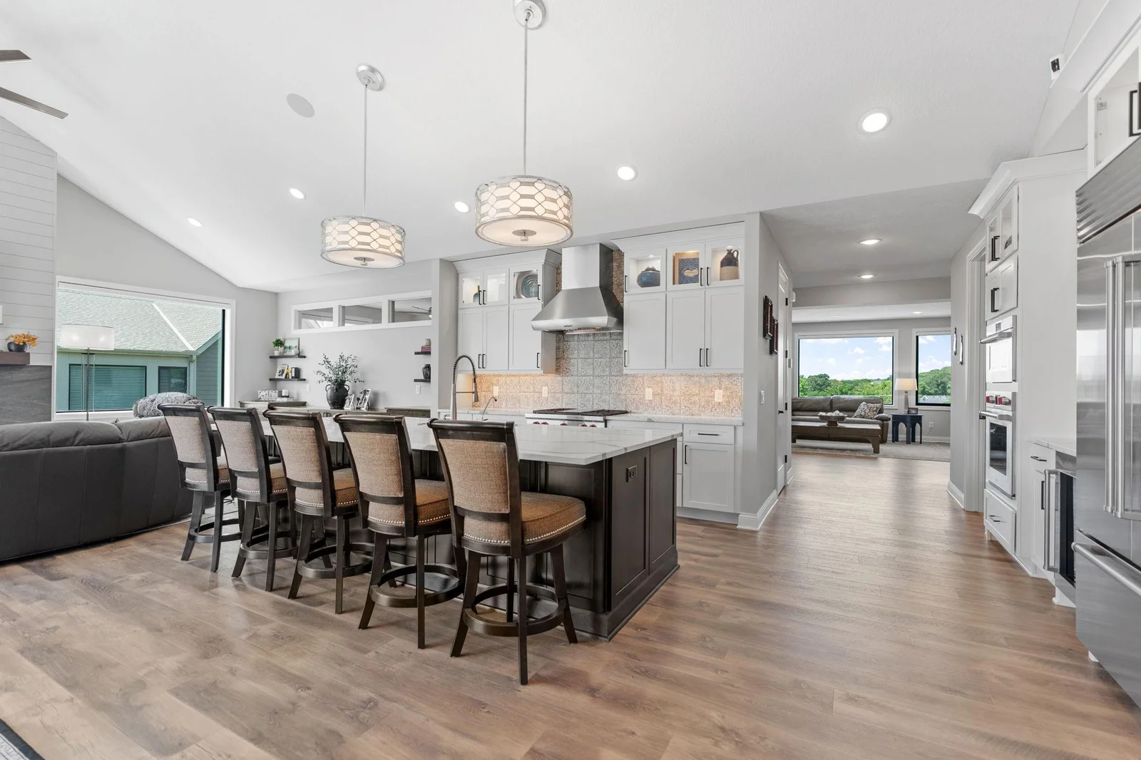 Kitchen features enameled cabinetry that features flat panel and glass doors with interior accent lighting, roll-out storage and an oversized “Eat-In” center island handcrafted in select alder
