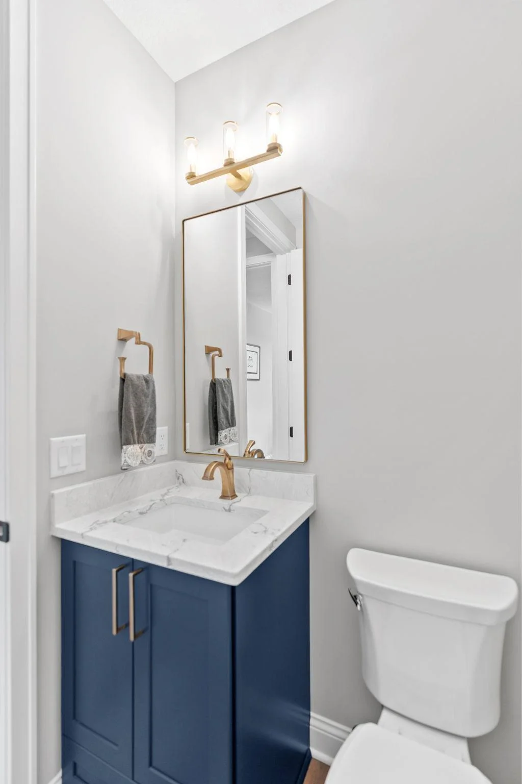1/2 bathroom on the main level features a enameled vanity with quartz top