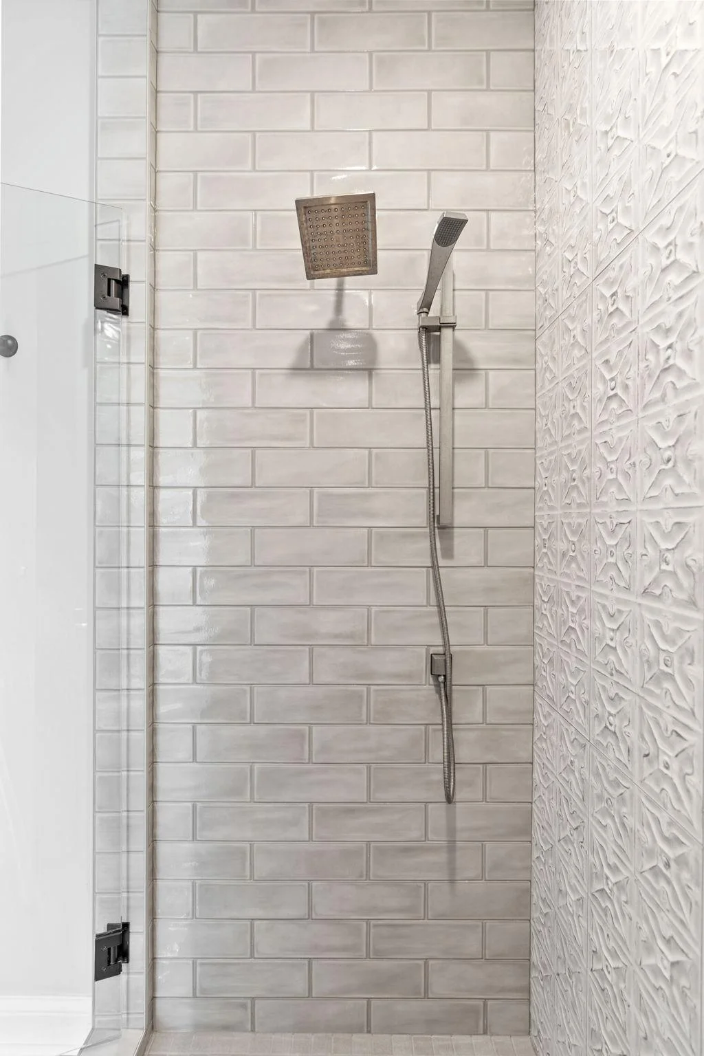Custom tile shower features subway and decorative wall tile and handshower