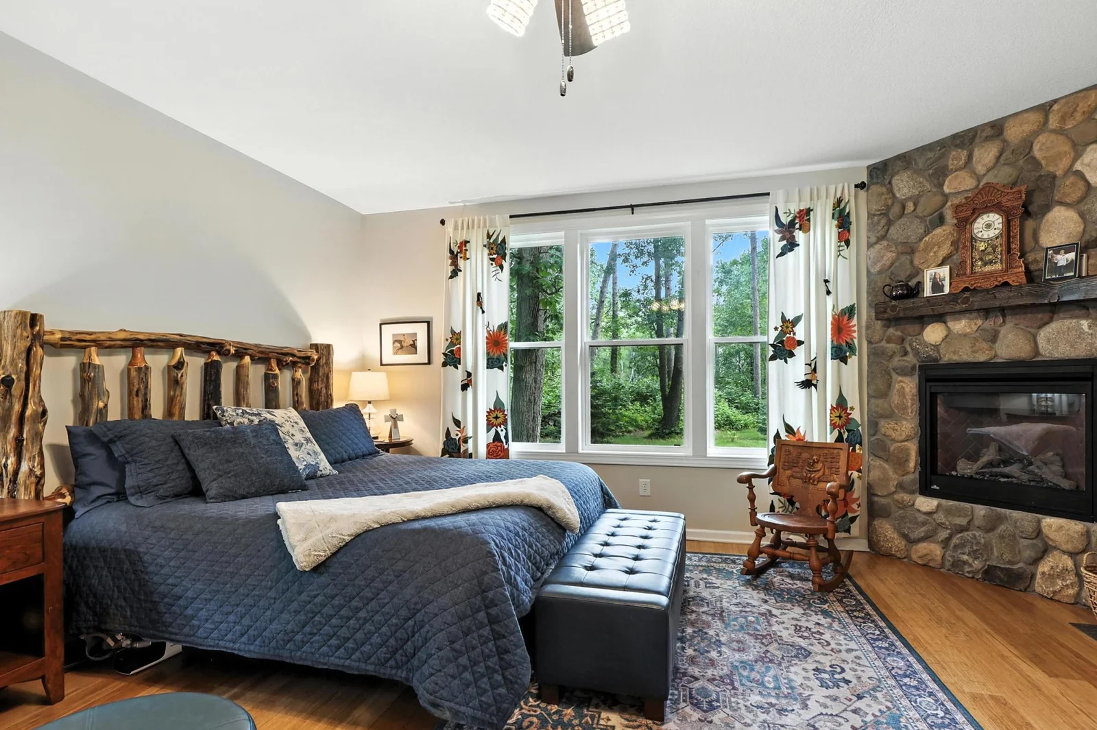 Wake up to serene forest views in this luxurious owner’s retreat, complete with a stone surround gas fireplace, custom area rug, and charming wood accents for a cozy, cabin-like feel.