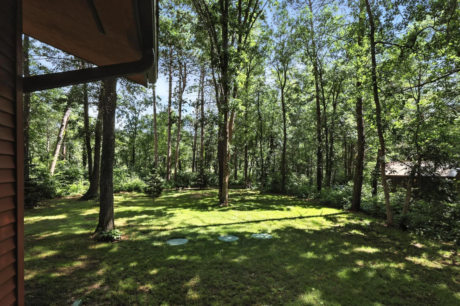 Enjoy peace and quiet with this lush backyard oasis framed by mature trees and space for lawn games or a future firepit.