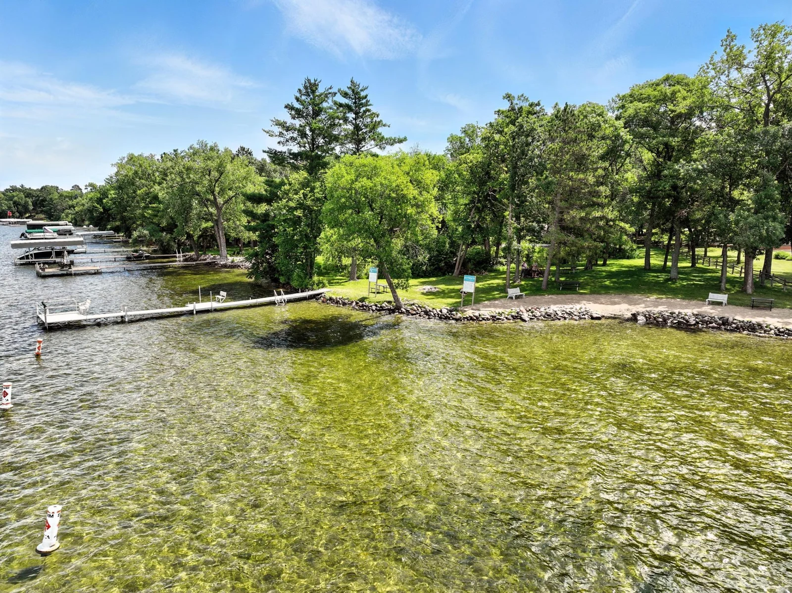 Enjoy level, sandy shoreline with picnic tables, benches, and lush green space perfect for lakeside relaxation.