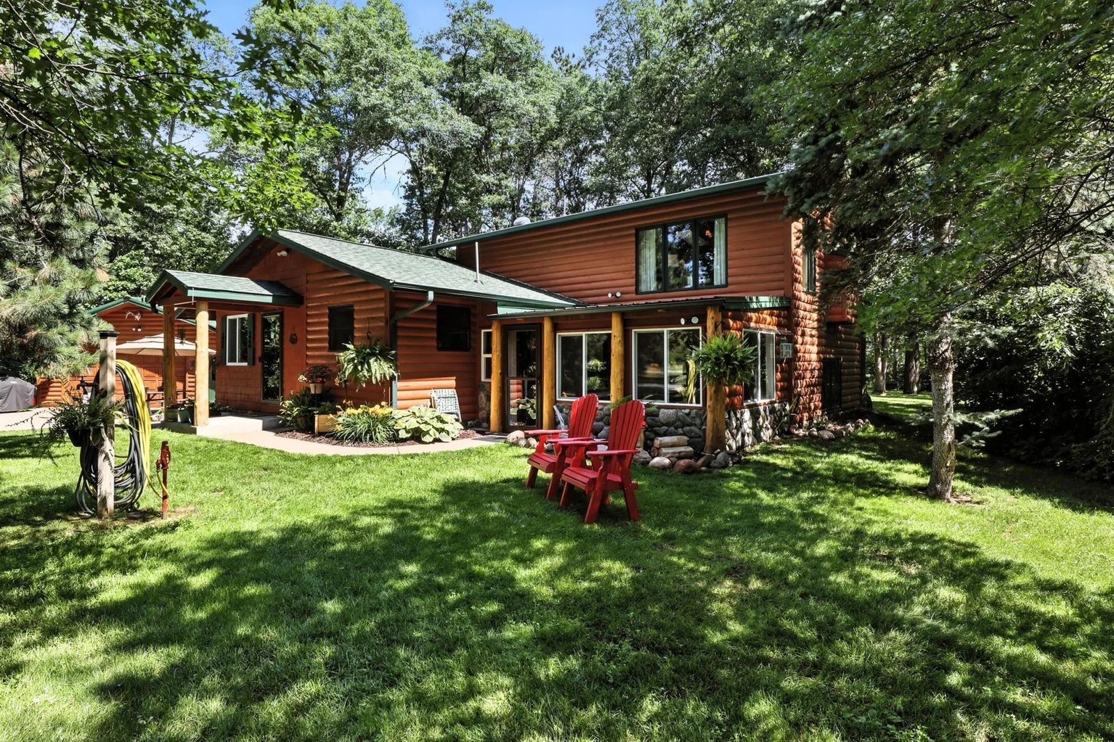 Expansive backyard surrounded by towering pines with cozy seating and natural privacy.