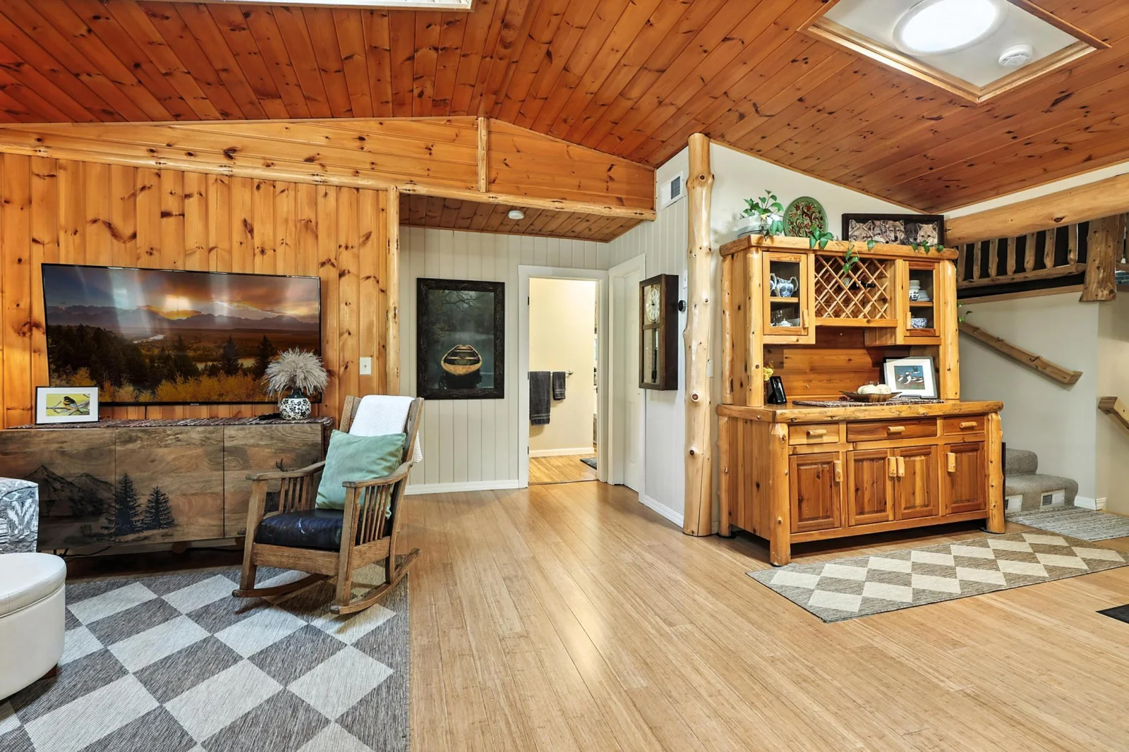 Another view of the living room reveals access to the hallway and stairs, with additional built-in cabinetry and a log-style hutch that enhances the home's rustic character.