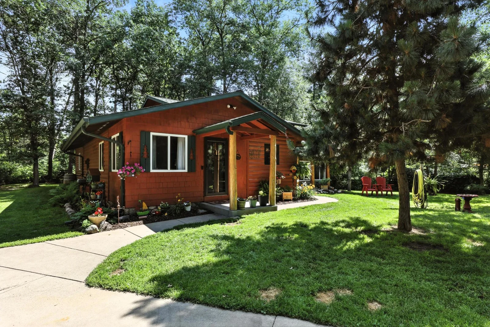 Inviting wood cabin with lush landscaping, front porch entry, and vibrant garden accents.
