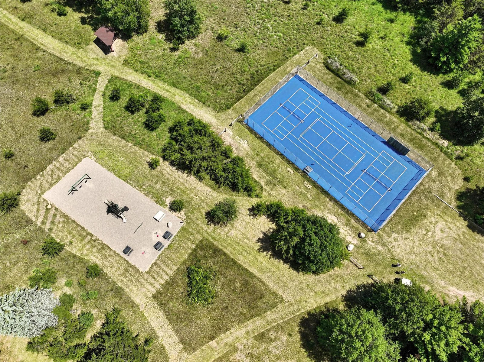 Drone shot captures both tennis courts and playground, highlighting easy access to fun and fitness trails