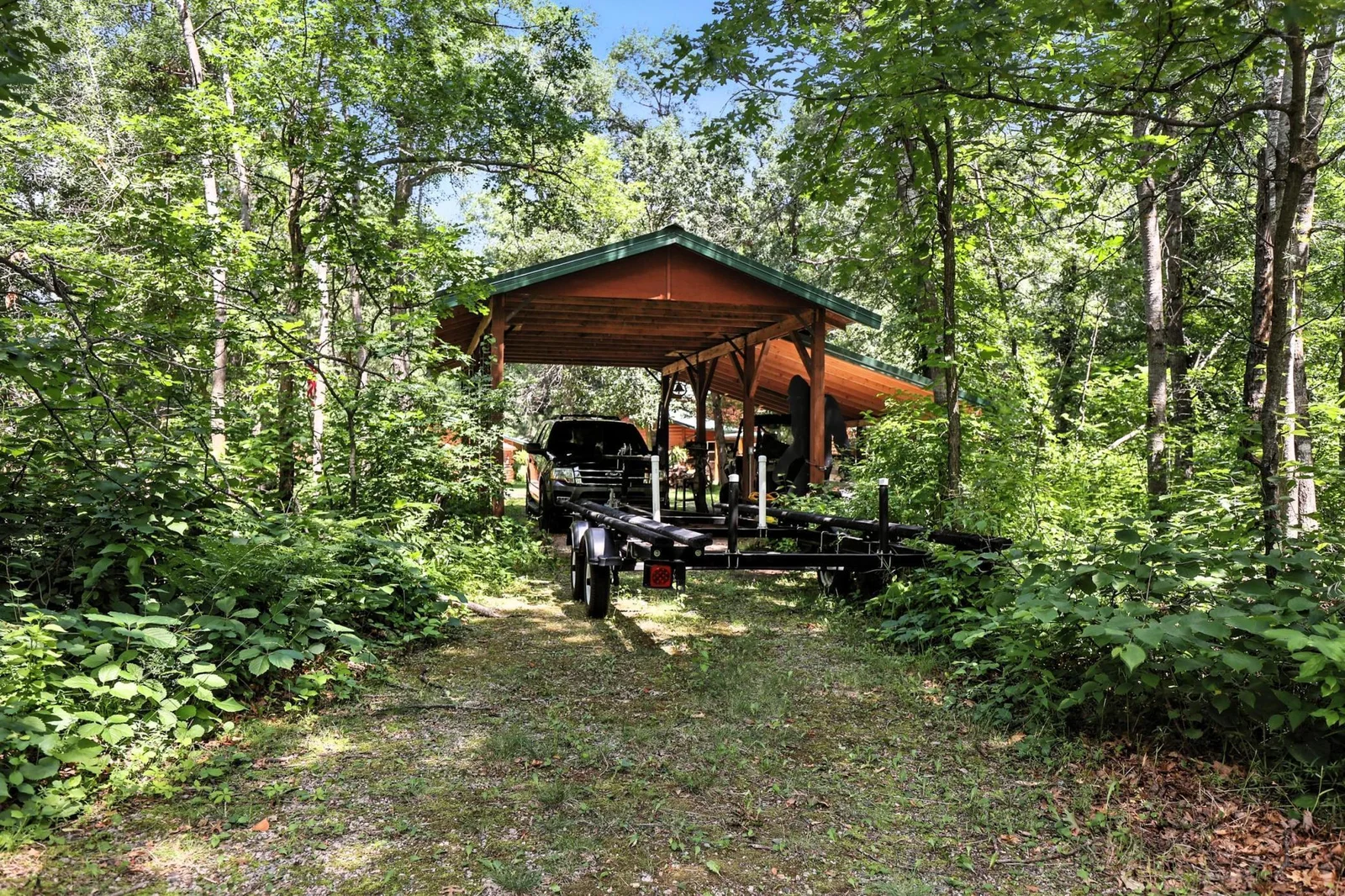 Oversized carport ideal for boats, trailers, or extra vehicles, surrounded by privacy and towering pines.