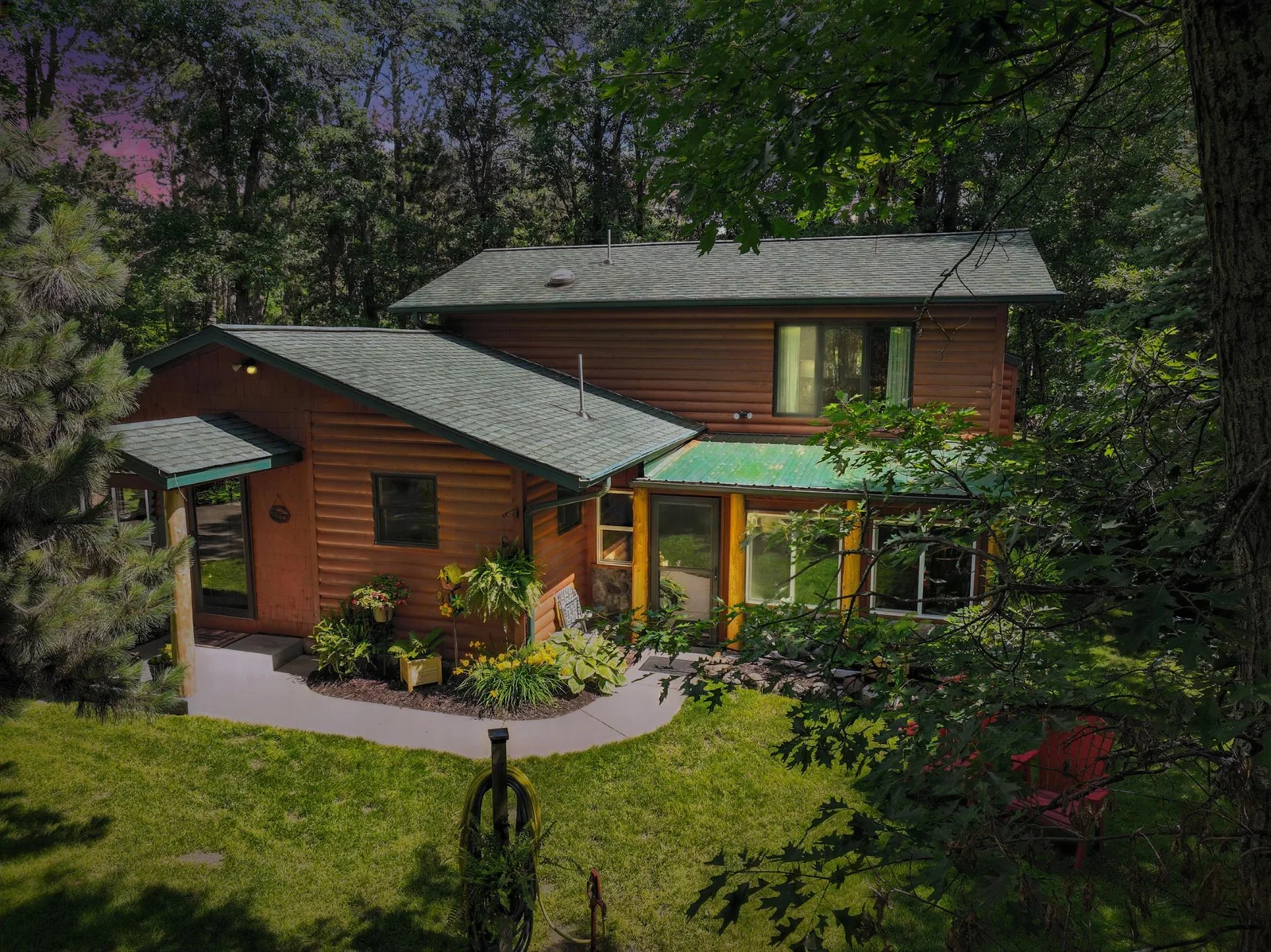 Beautiful dusk exterior highlighting log-style charm, natural landscaping, and wooded privacy.