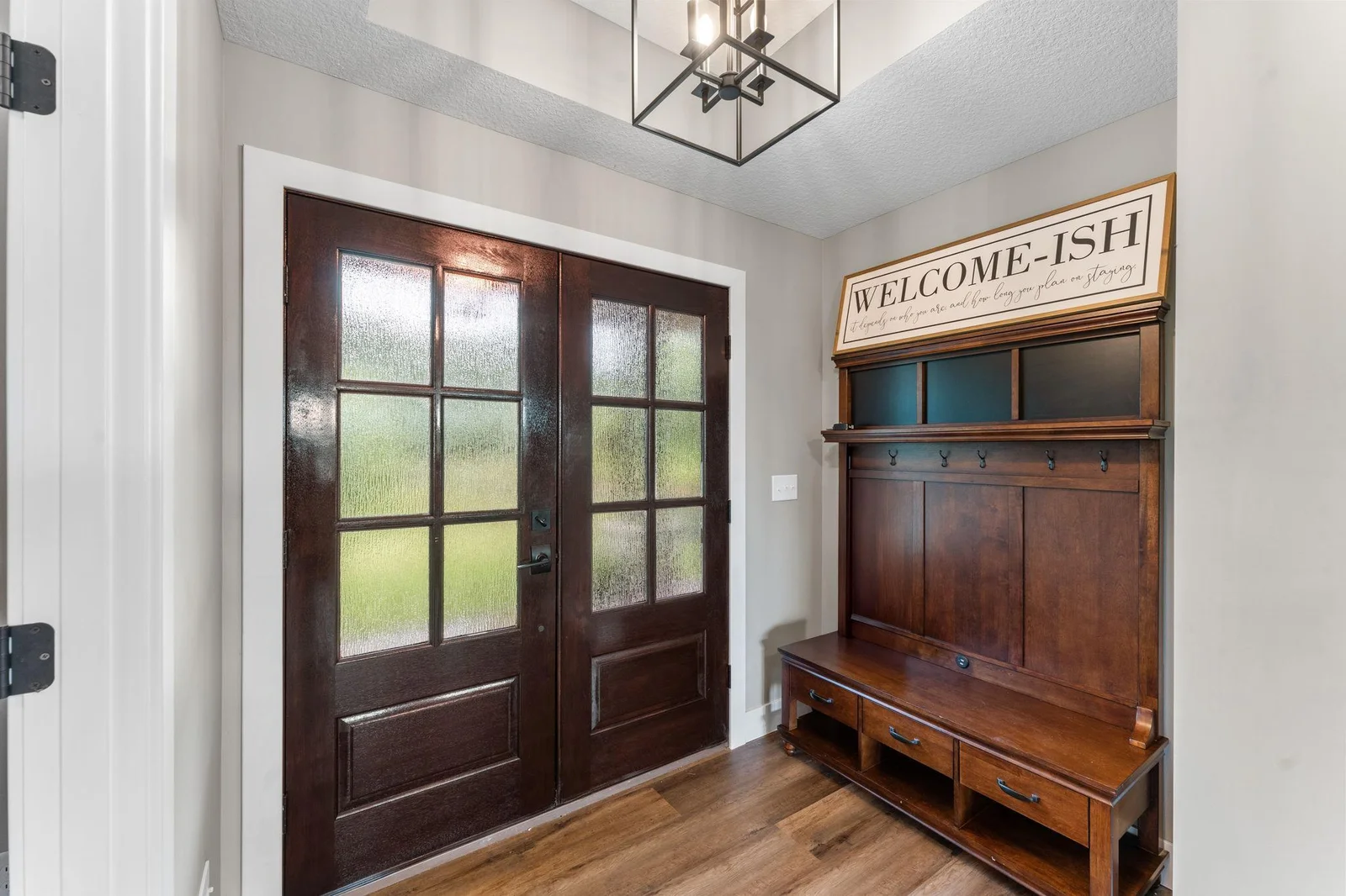 A warm and welcoming entryway featuring rich wood tones and stylish double doors.