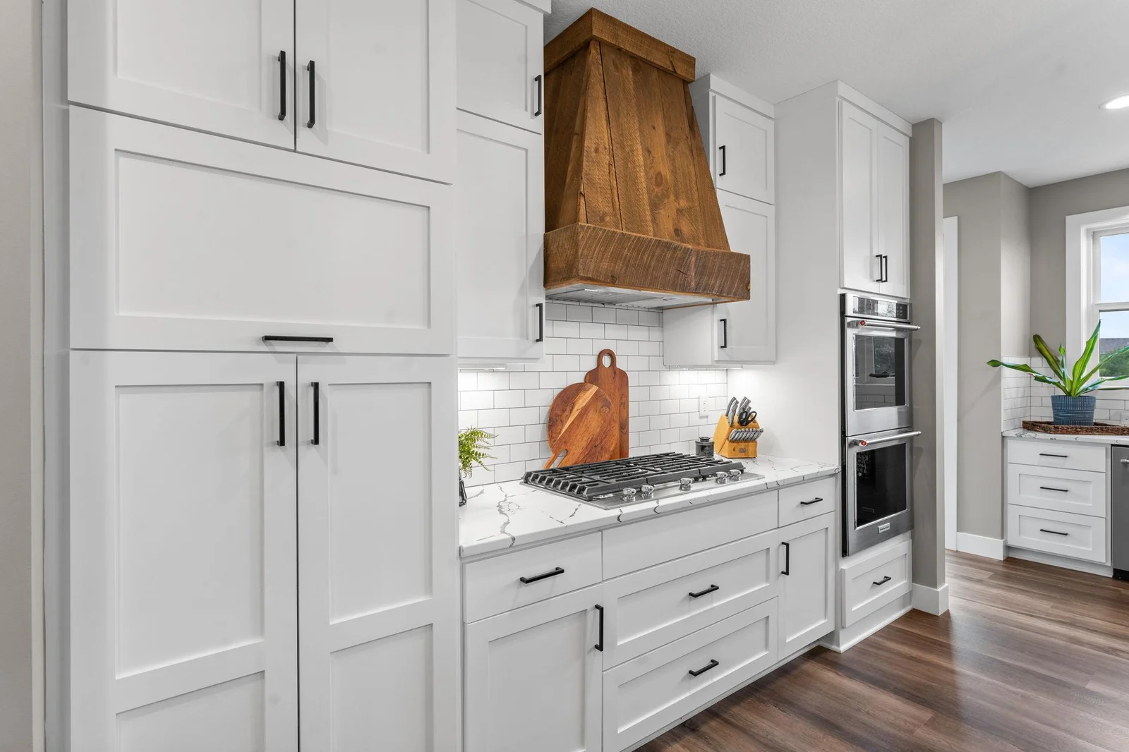This gourmet kitchen is thoughtfully designed with custom cabinetry, stone countertops, a gas cooktop, double ovens, and an oversized walk-in pantry.