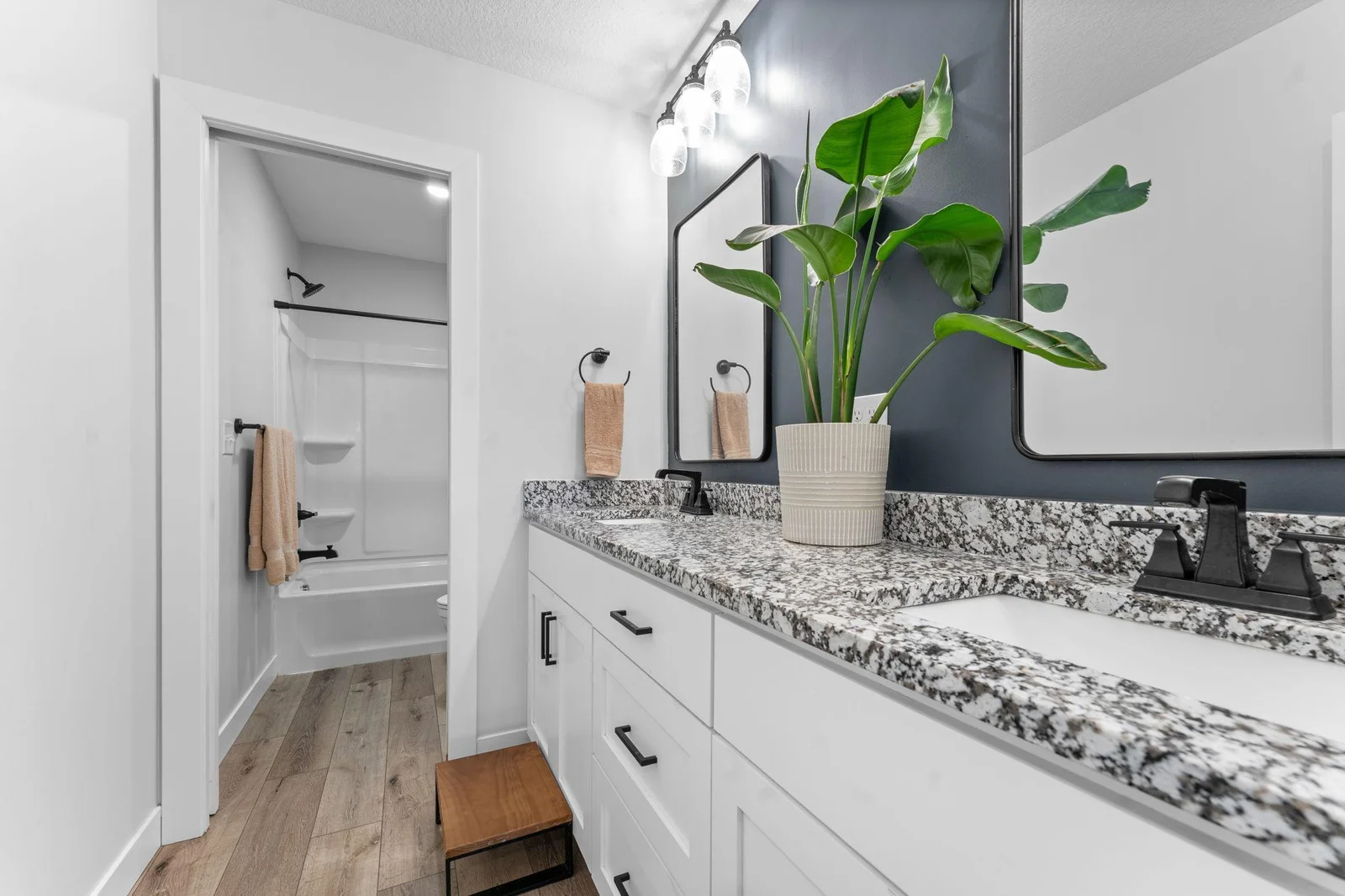 The shared upper-level full bathroom, conveniently located just steps from all bedrooms, features a double vanity with granite countertops, luxury plank flooring, and a tub-shower combination.