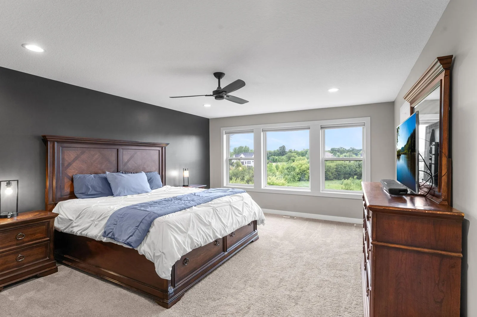 The spacious primary suite features plush carpeting, a ceiling fan, large windows, a private full bathroom, and a generous 15x12 walk-in closet.