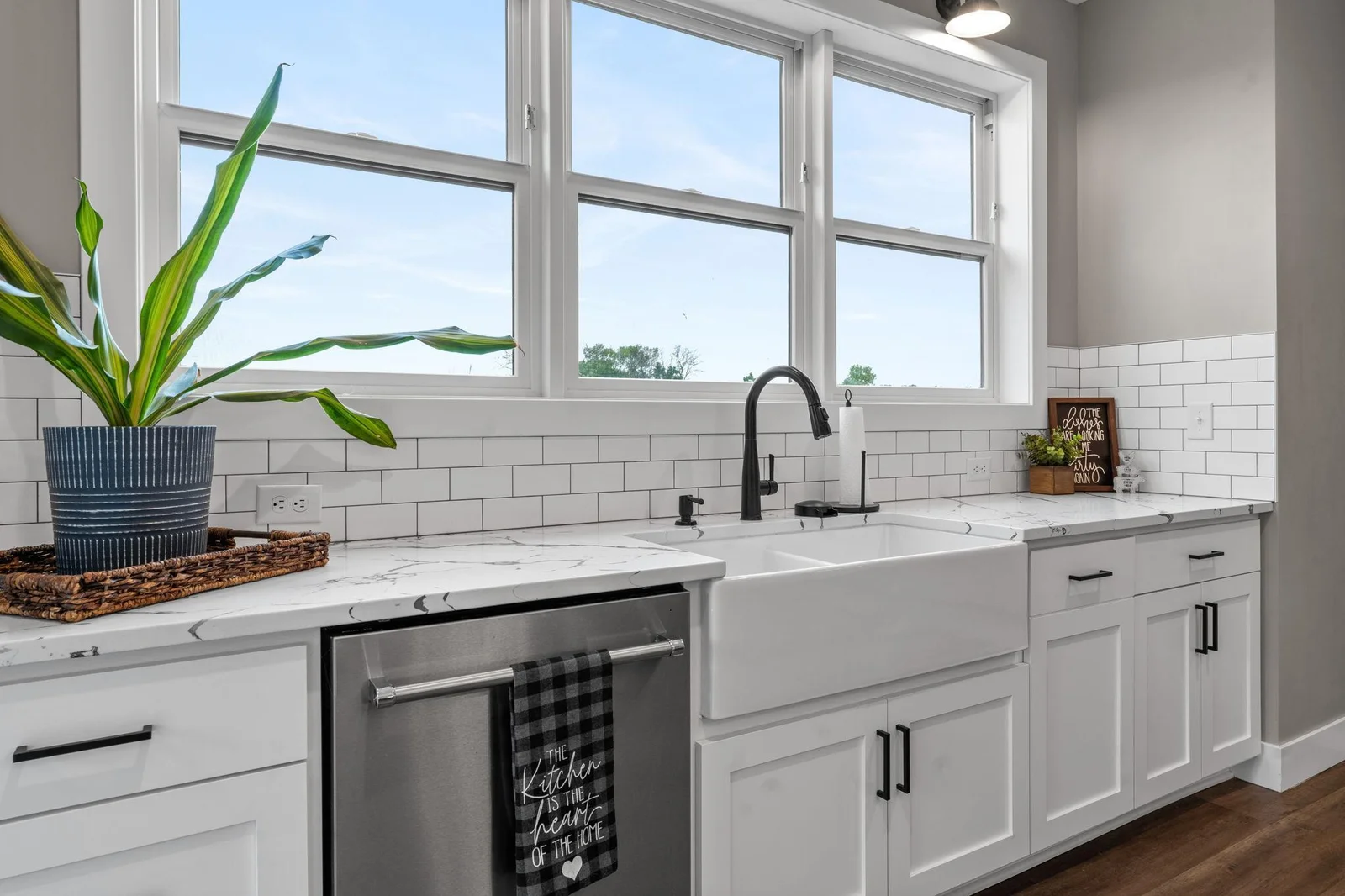 This charming kitchen space includes a deep farmhouse sink, sleek subway tile backsplash, and expansive windows offering serene backyard views.