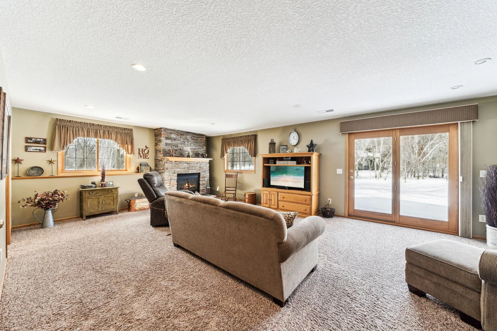 Walkout lower level family room with corner stone fireplace and sliding doors out to the backyard.