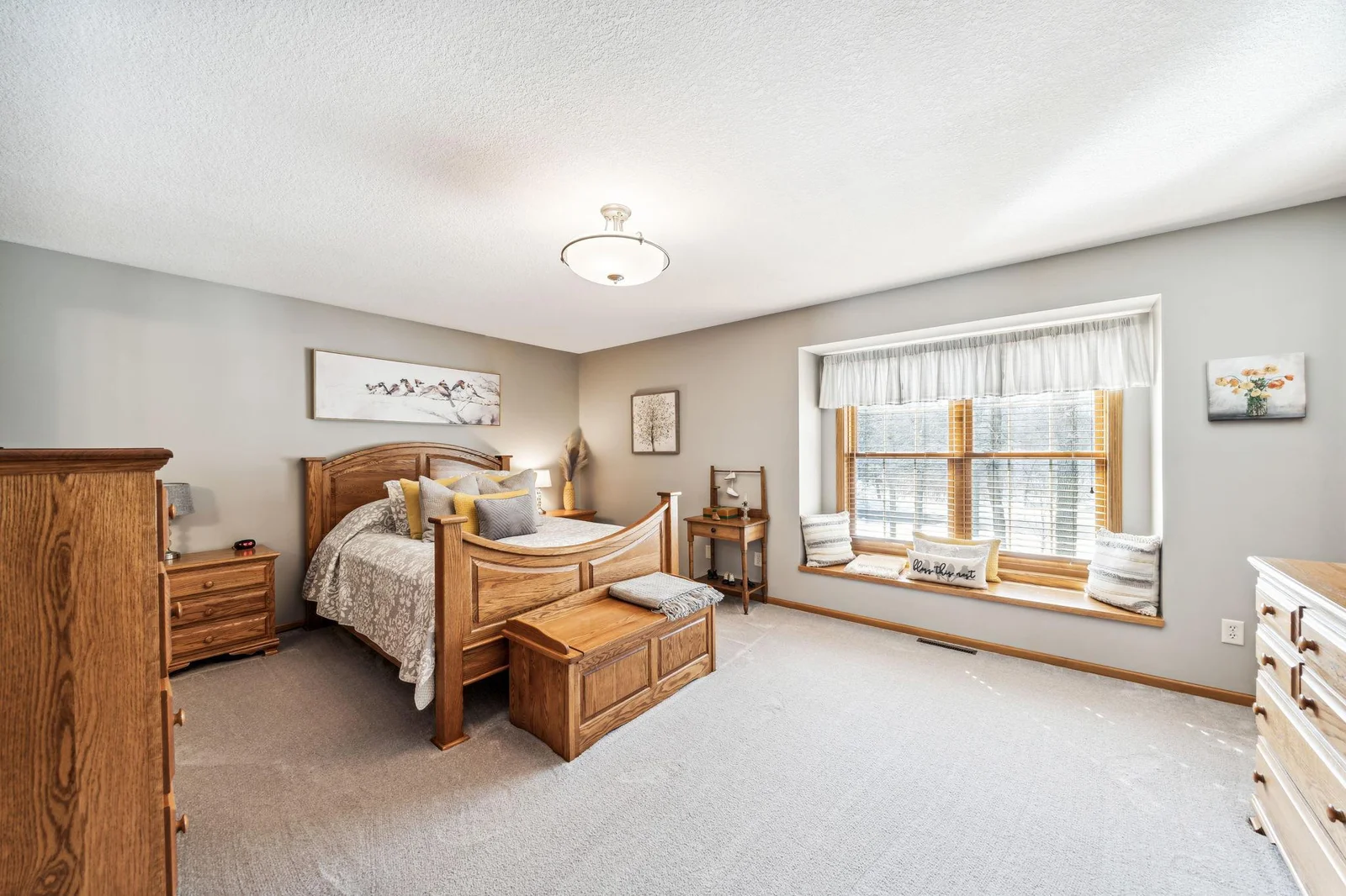 Another view of the primary bedroom with large window and bench seat.