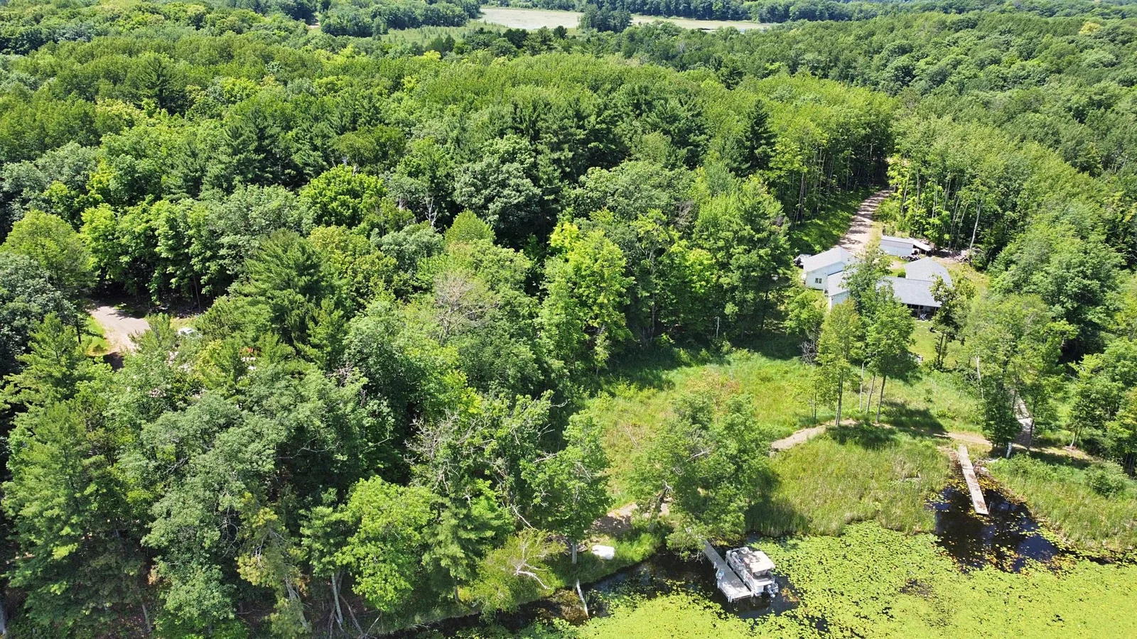 Lakeshore of lot with dock and boat in lower right (not included)