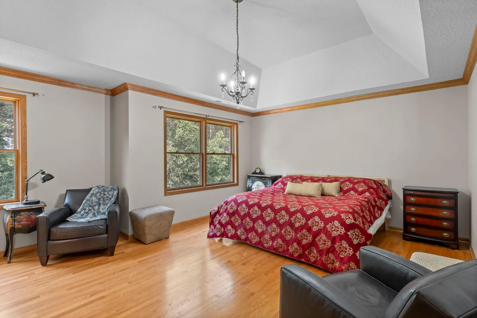 The upper level primary bedroom is a luxurious space with large windows and a vaulted ceiling