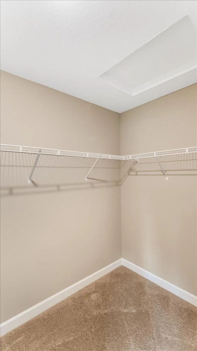 Walk in closet with built in shelves and hanger space.